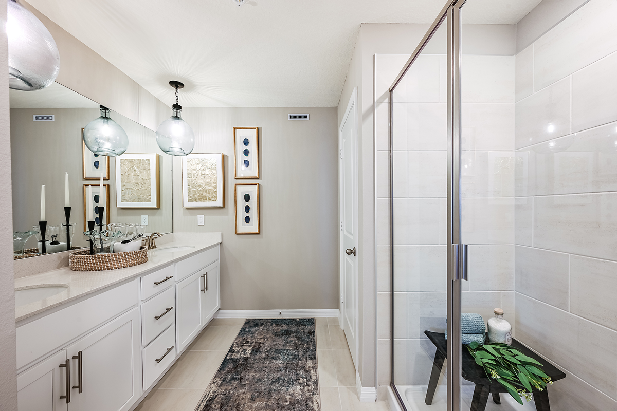 primary bathroom with dual sink vanity and shower