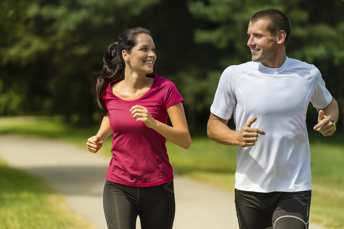 man and woman running on a trail in a park