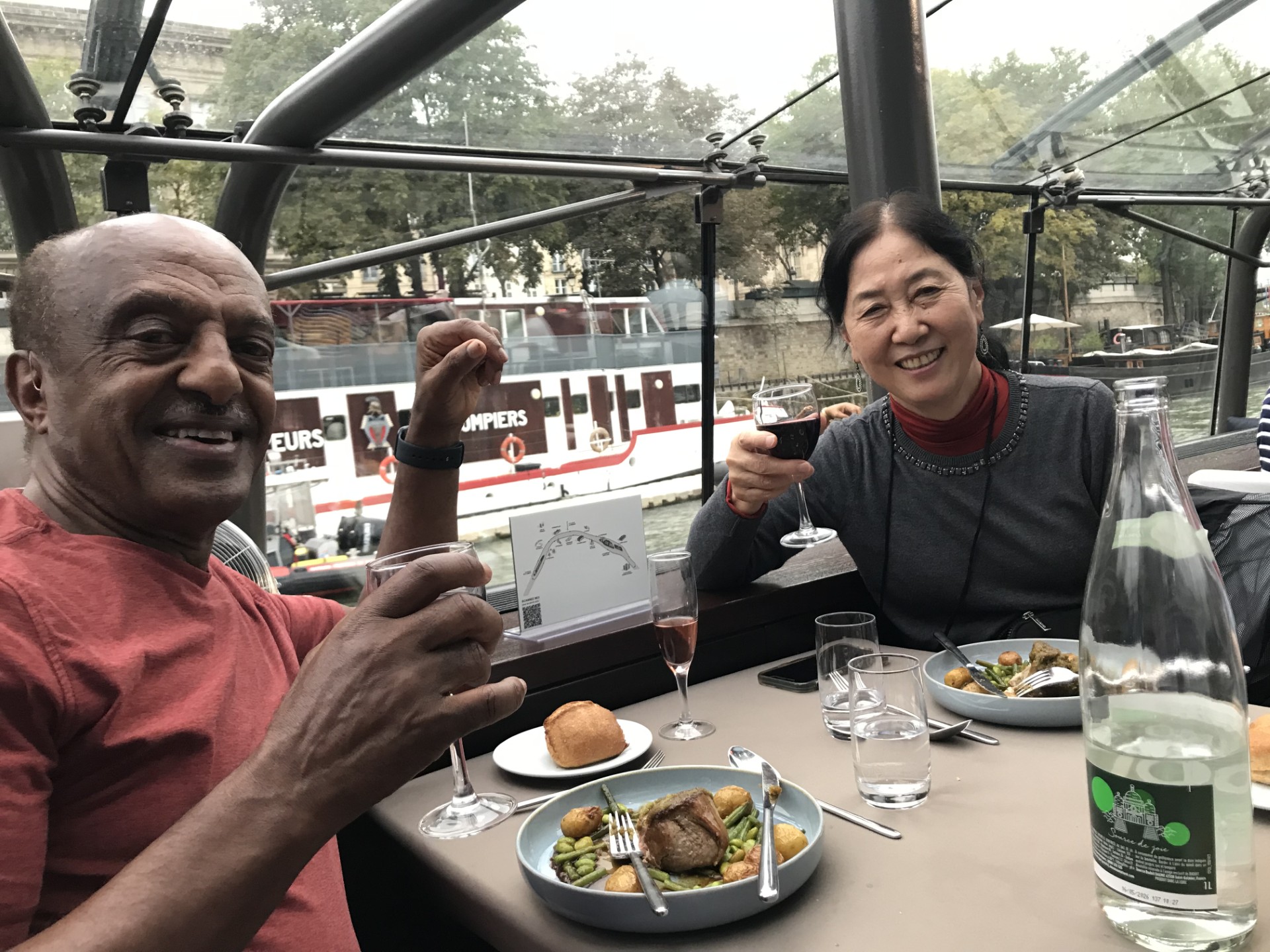 Fumie and Ahmed raise their glasses at a meal in France