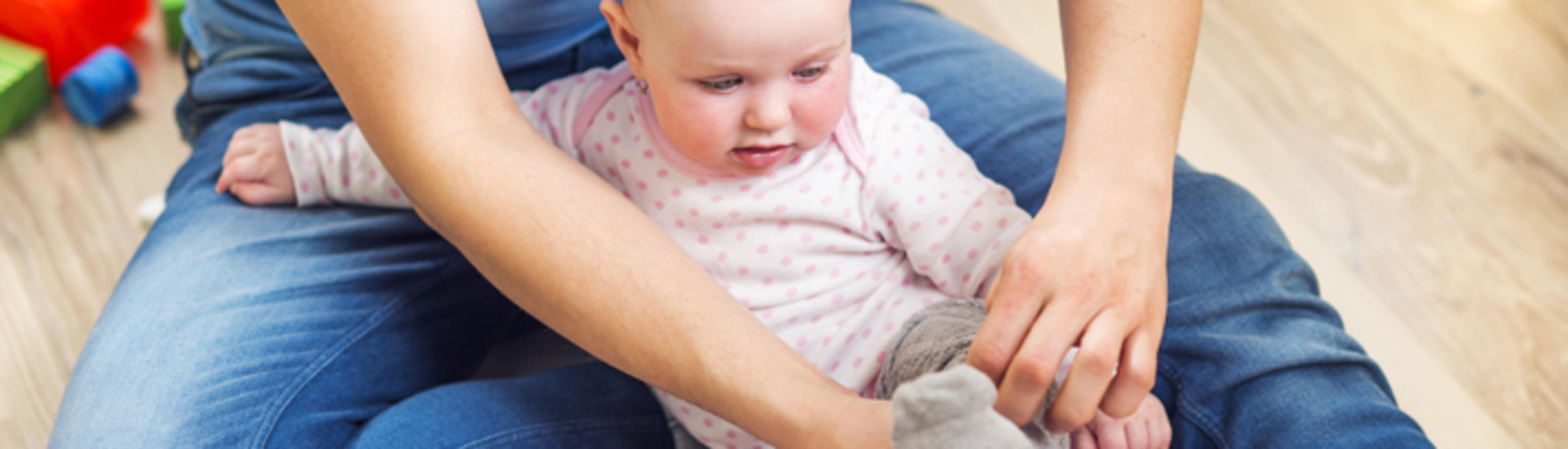 Parent putting socks on baby.