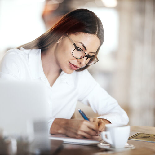 Une femme aux cheveux longs et aux lunettes écrit quelque chose