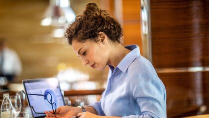 Female business owner reviewing financial report on a laptop in a restaurant