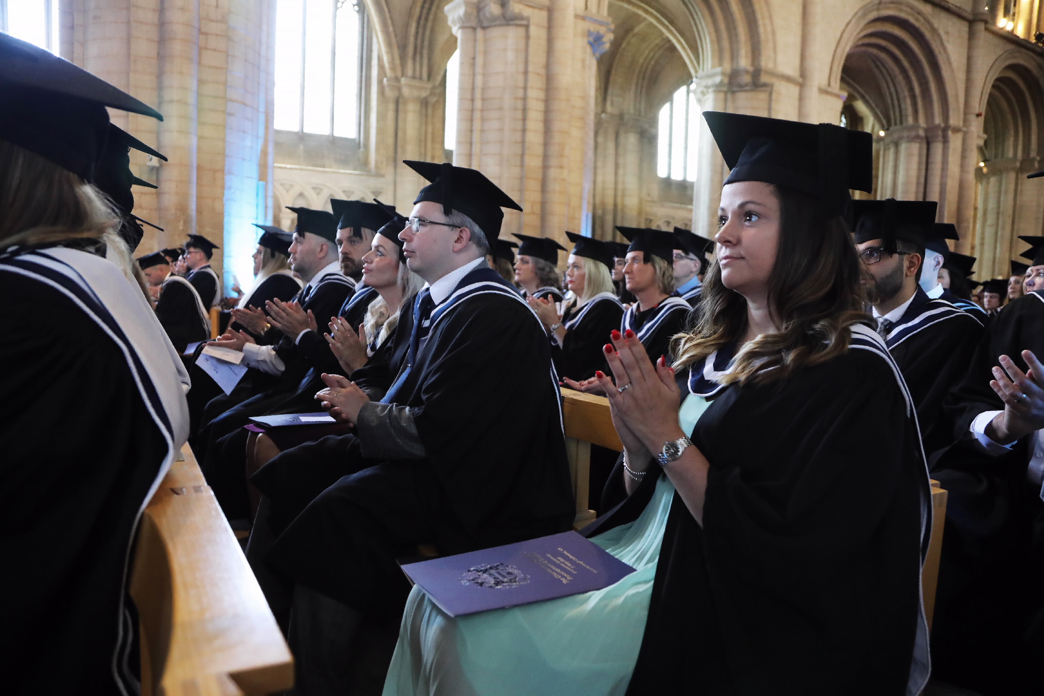 Graduates seated and clapping during the ceremony