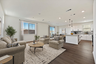 great room with a couch and coffee table leading to the dining room and kitchen