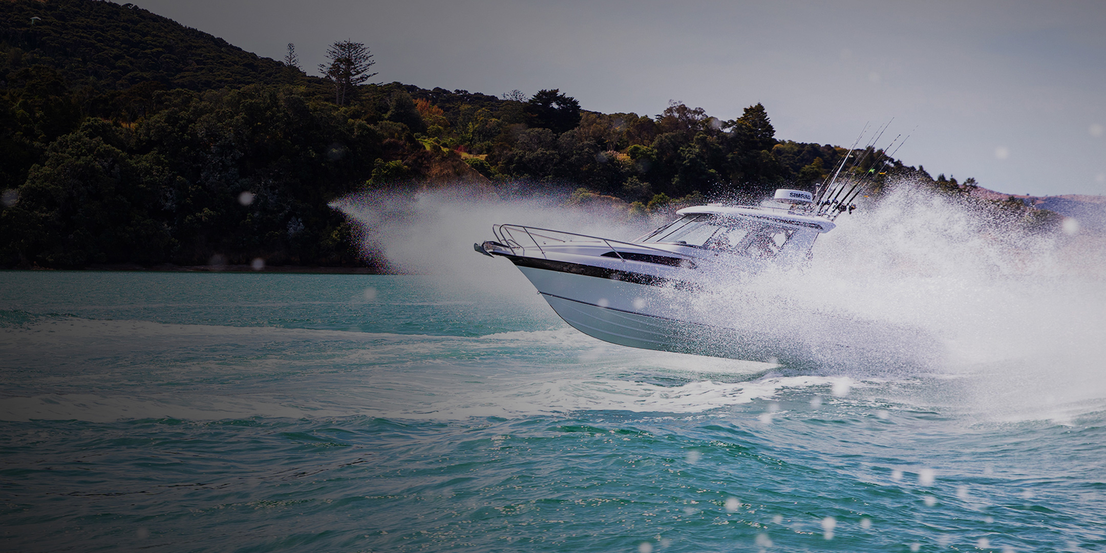 A speedboat sailing along the coastline kicking up surf