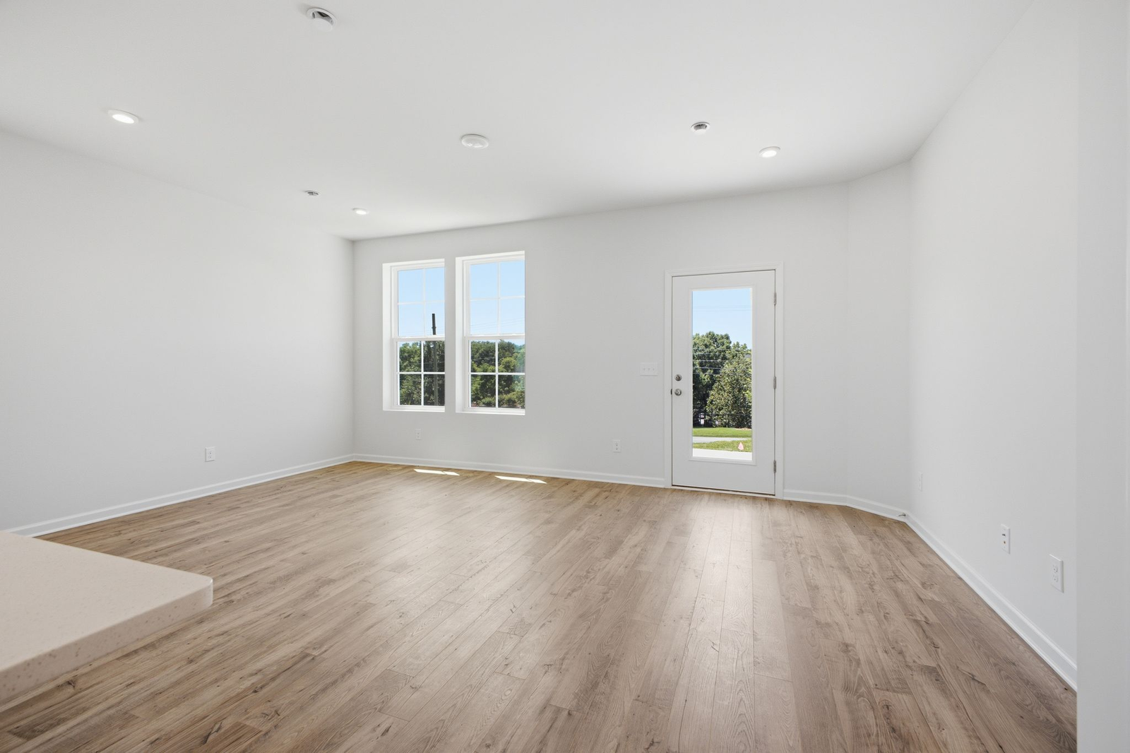 great room with wood floors, white walls, and large windows