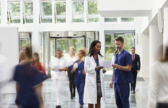 Hospital staff in lobby with people in motion