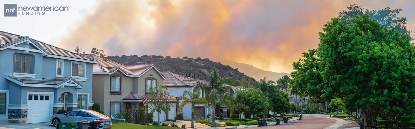 A wildfire in the distance of several homes on a residential block.