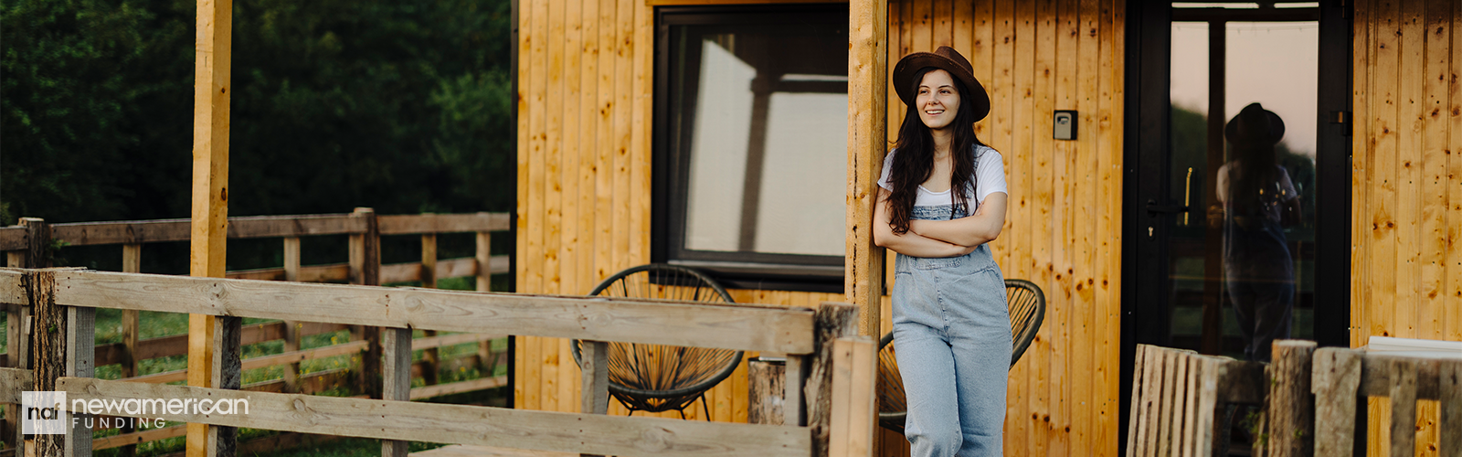 A woman outside of a tiny, wooden home.