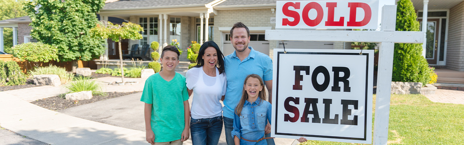 Family in front of for sale sign