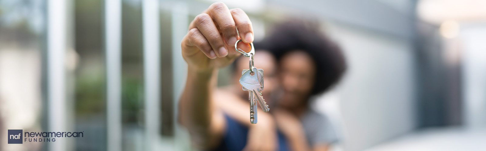 A couple embracing hold up the keys to their new home.