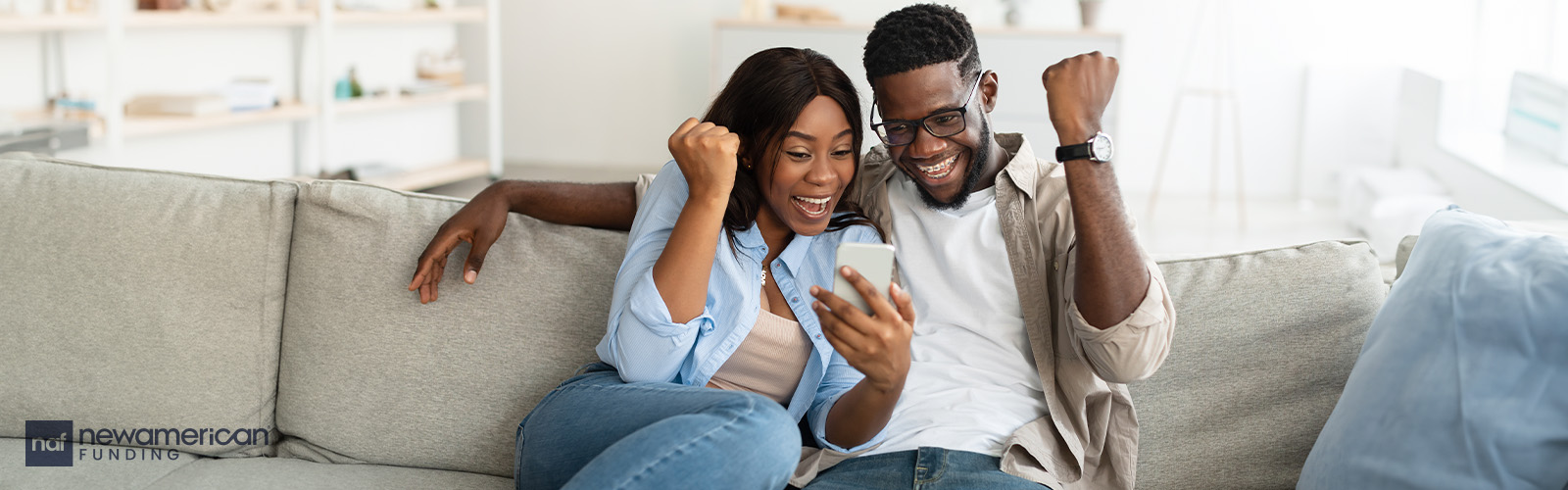 A Black couple celebrates on a couch.