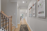 entryway with light wood floors, study with blue accent wall, and wood stairs with oak railing