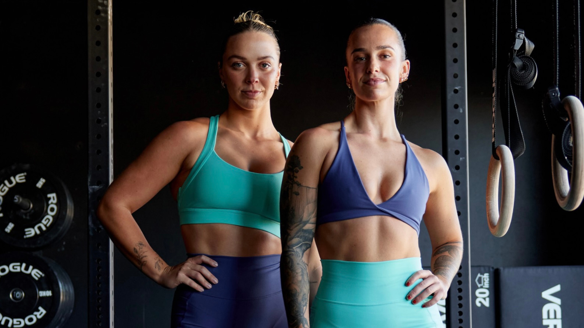 Two women standing side-by-side wearing matching gym clothing