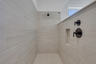primary bathroom with large walk-in shower and light tile