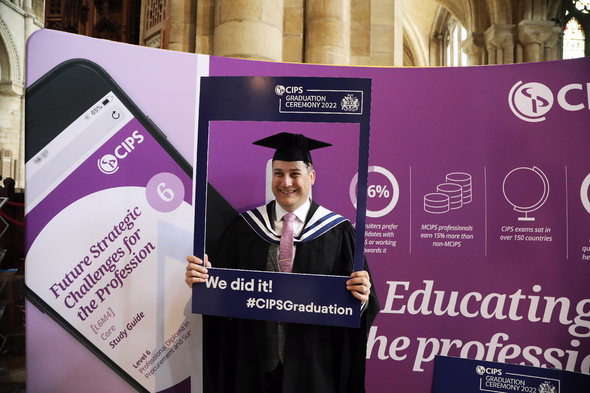 Male graduate smiling behind a CIPS photo frame