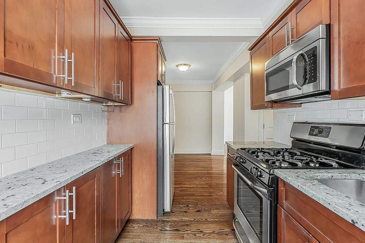 A Manhattan skinny kitchen with wood cabinets.