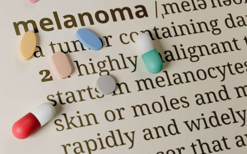 page with definition of melanoma with various pills sitting on top