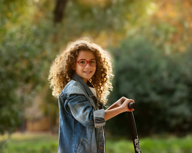 Girl with curly hair and red glasses playing outdoors