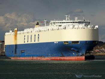 A photo shows a large vessel ship sailing through the sea. It's painted white and blue with EUKOR written on the side. The ship hold containers and features a Panamanian flag atop it.