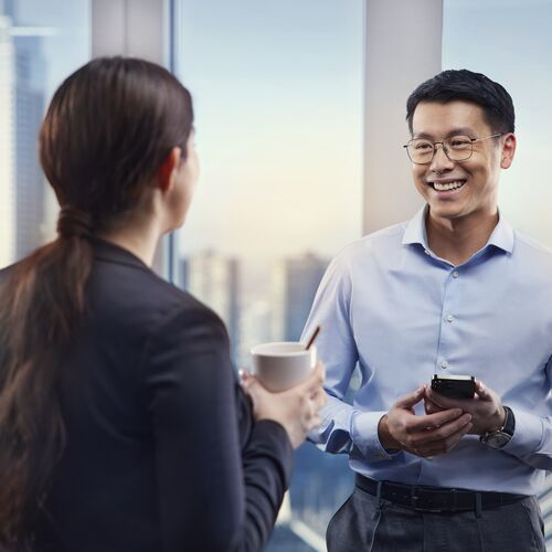 Asian man in nice suit with glasses smiles at a woman