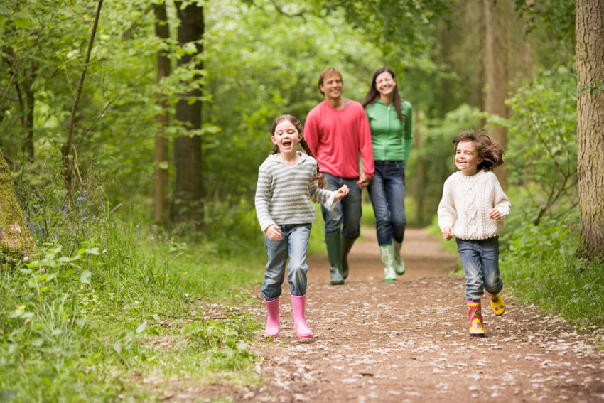 Družina na družinski dan uživa na sprehodu skozi bližnji gozd.