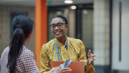Two women at a table talking over a clipboard