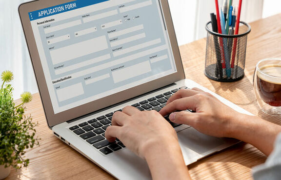 Man filling out an online job application on a laptop at a desk