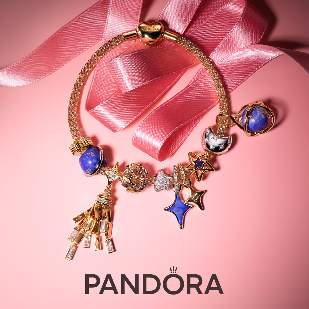 image of pandora bracelet sitting on pink background with pink ribbon around it