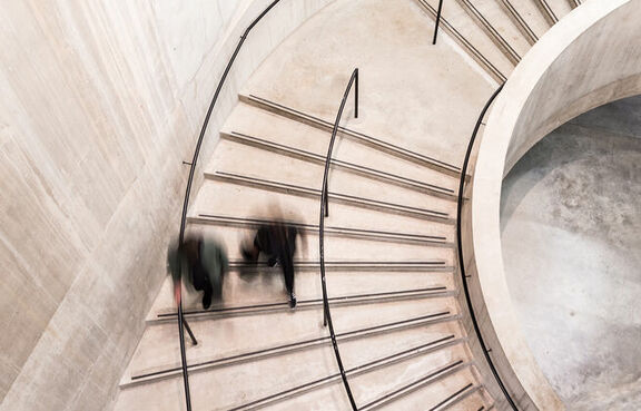 Blurred images of people walking down a large staircase