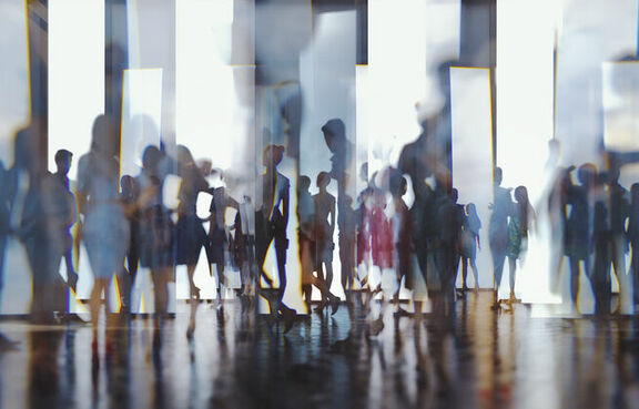 Silhouettes of people walking reflected off glass panels