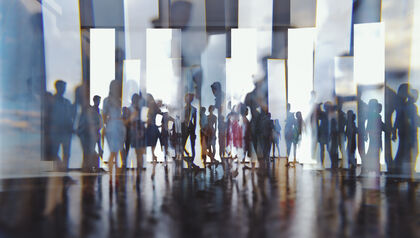 Silhouettes of people walking reflected off glass panels