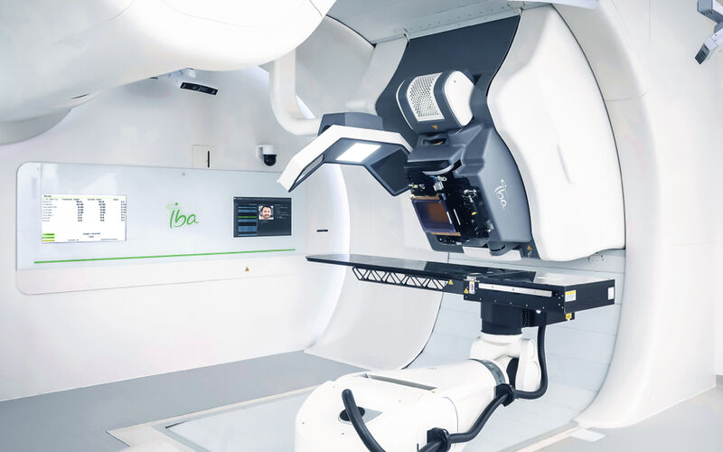 A photo shows a large white machine known as a ProteusONE. The machine features a large gantry, imaging equipment and table for patients to lie upon.