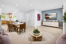 great room with light wood floors, slate blue wall behind television, round wood coffee table, and view of dining table with six brown chairs