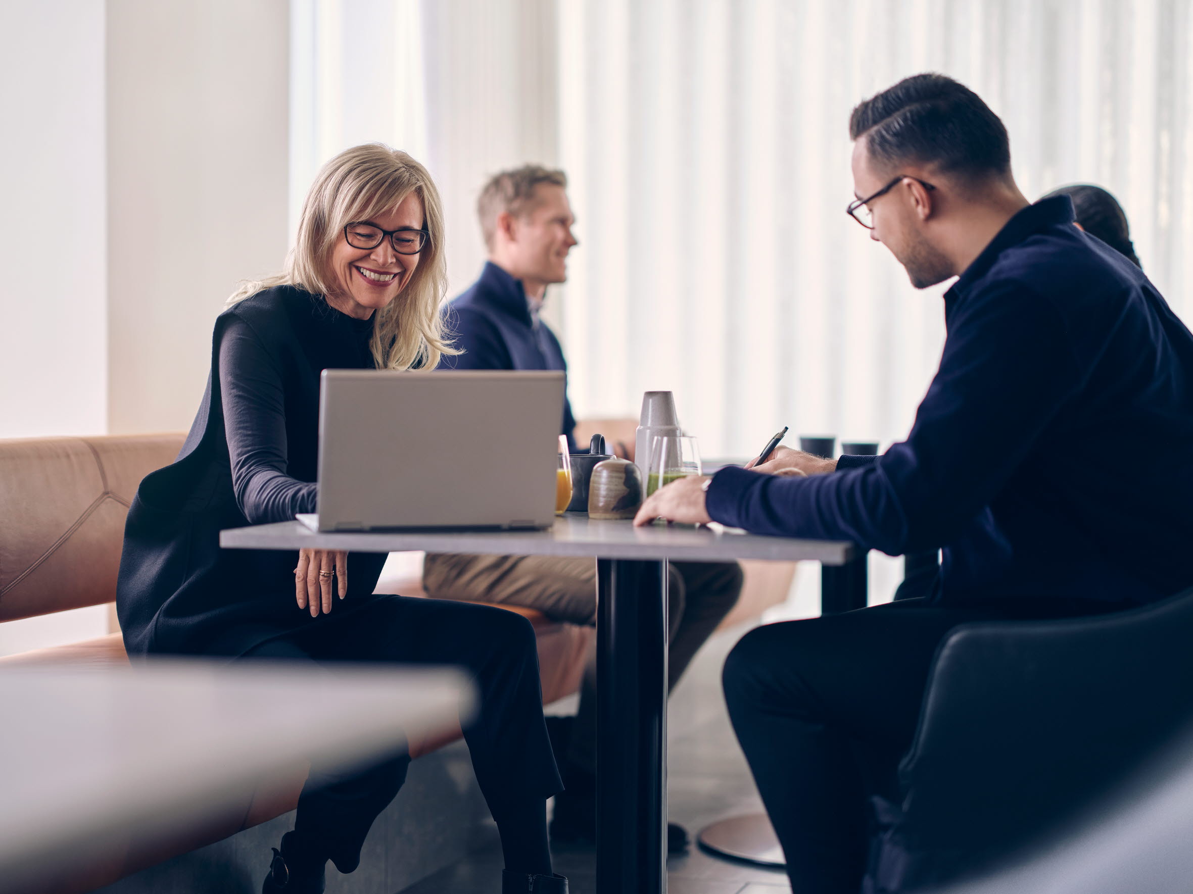 Four people sitting on a table in a meeting room in front of a window