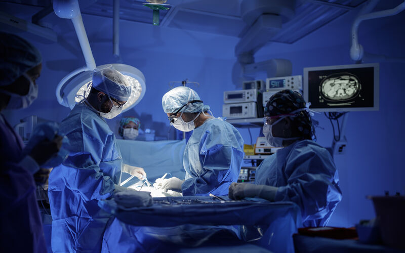 Surgeons gather around an operating table in an OR