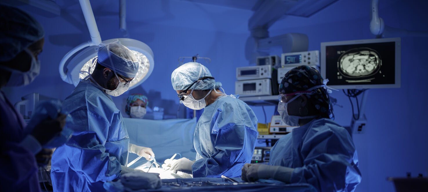 Surgeons gather around an operating table in an OR