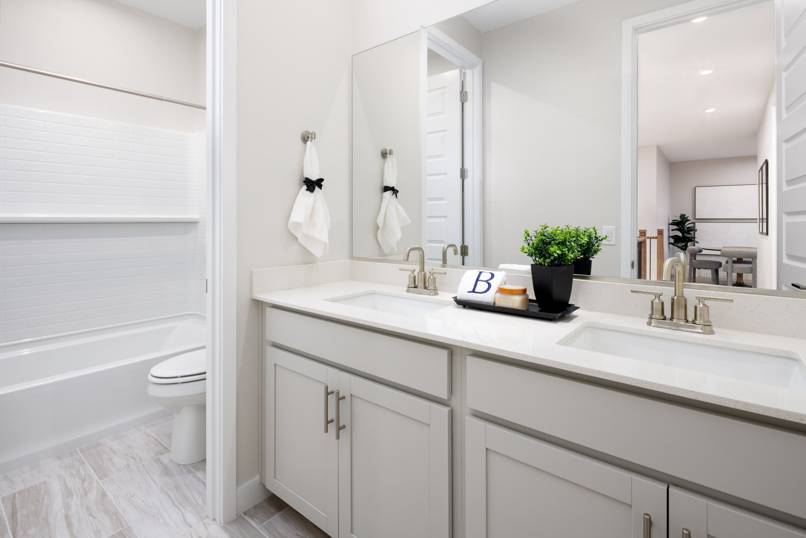 bathroom with light grey cabinets, double sink, and brushed nickel faucets