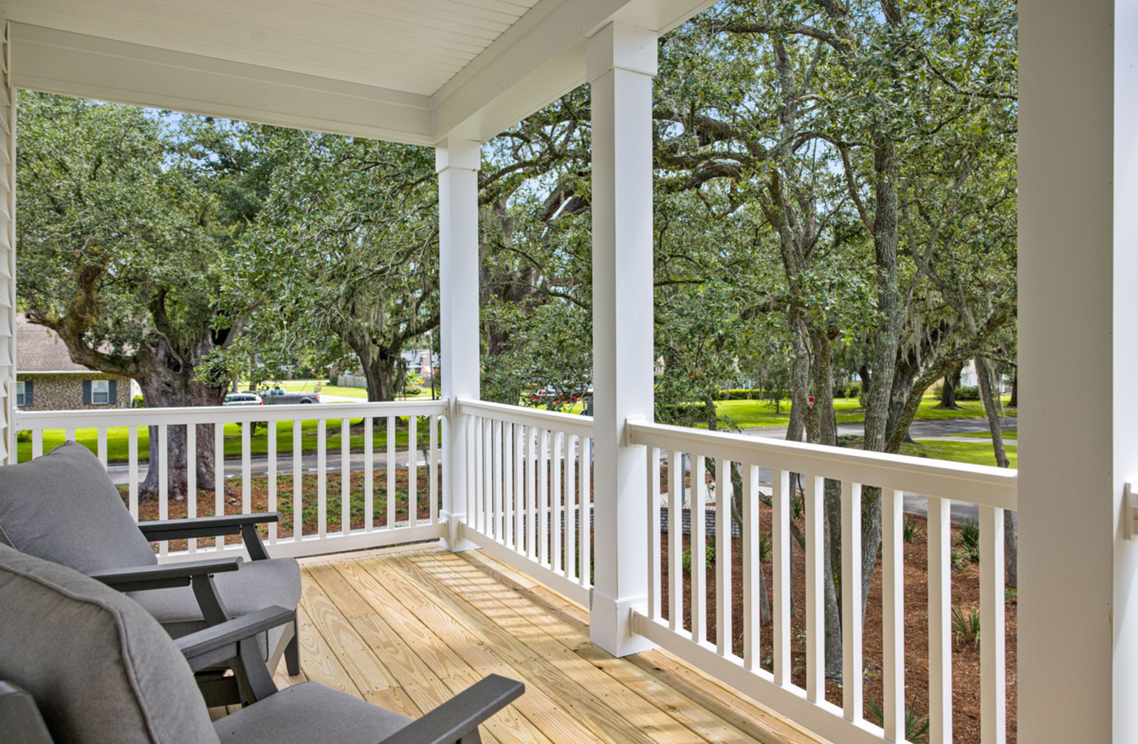 covered porch with chairs overlooking oak trees