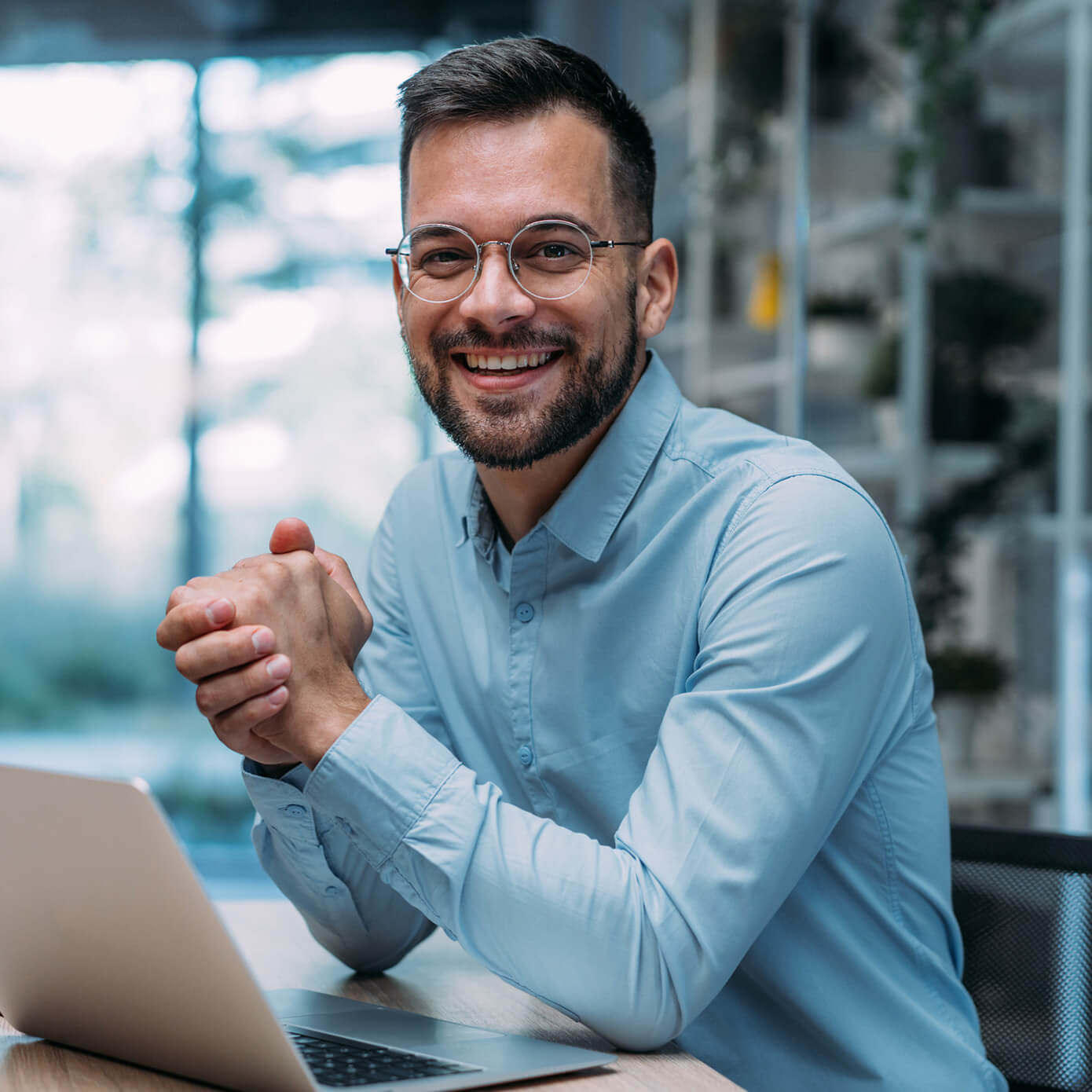 Sales-Leader-1911521695-1390x1390.jpg Image of a man smiling while sitting in front of his laptop computer.