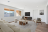 open-concept space with a large off-white couch, wooden coffee table, and a large black tv console table