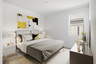 bedroom with a large bed with grey bed covers, glass nightstands, and yellow color accents