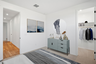 bedroom with a large grey rug, a light teal dresser, and ocean artwork