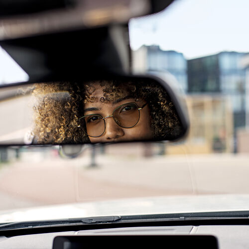Frau trägt beim Autofahren photochrome HOYA-Gläser