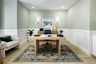 study with light green walls, wood floors, light wood desk, potted plant in corner, and white chair with green pillow