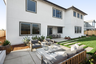 backyard with grassy area, wood & gray outdoor furniture, potted plants, and covered patio
