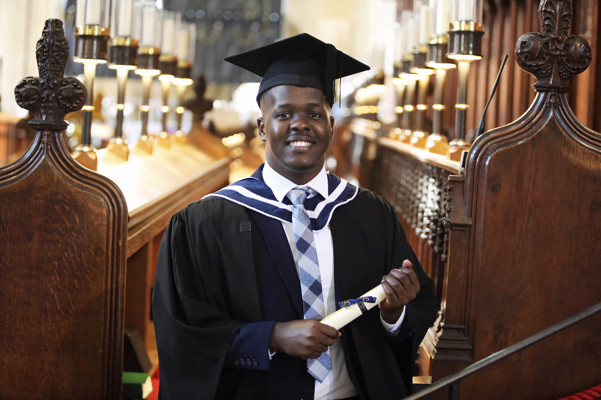 Smiling graduate holding his diploma inside the cathedral