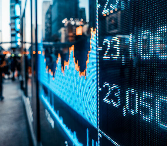 Display showing stock prices and line graph on a busy street