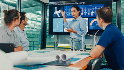 Team of engineers sitting at a table looking at a presentation filled with graphs