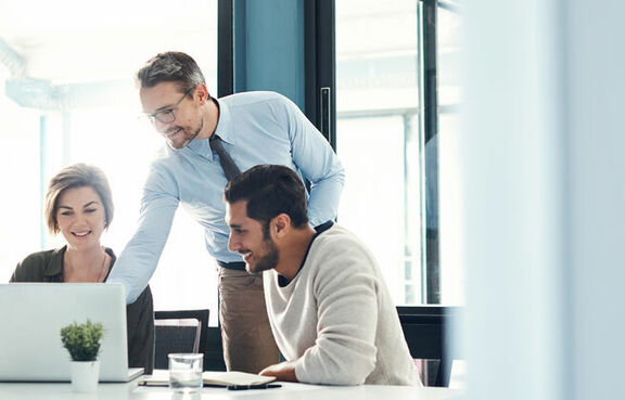 Coworkers sitting at a desk looking at a laptop together